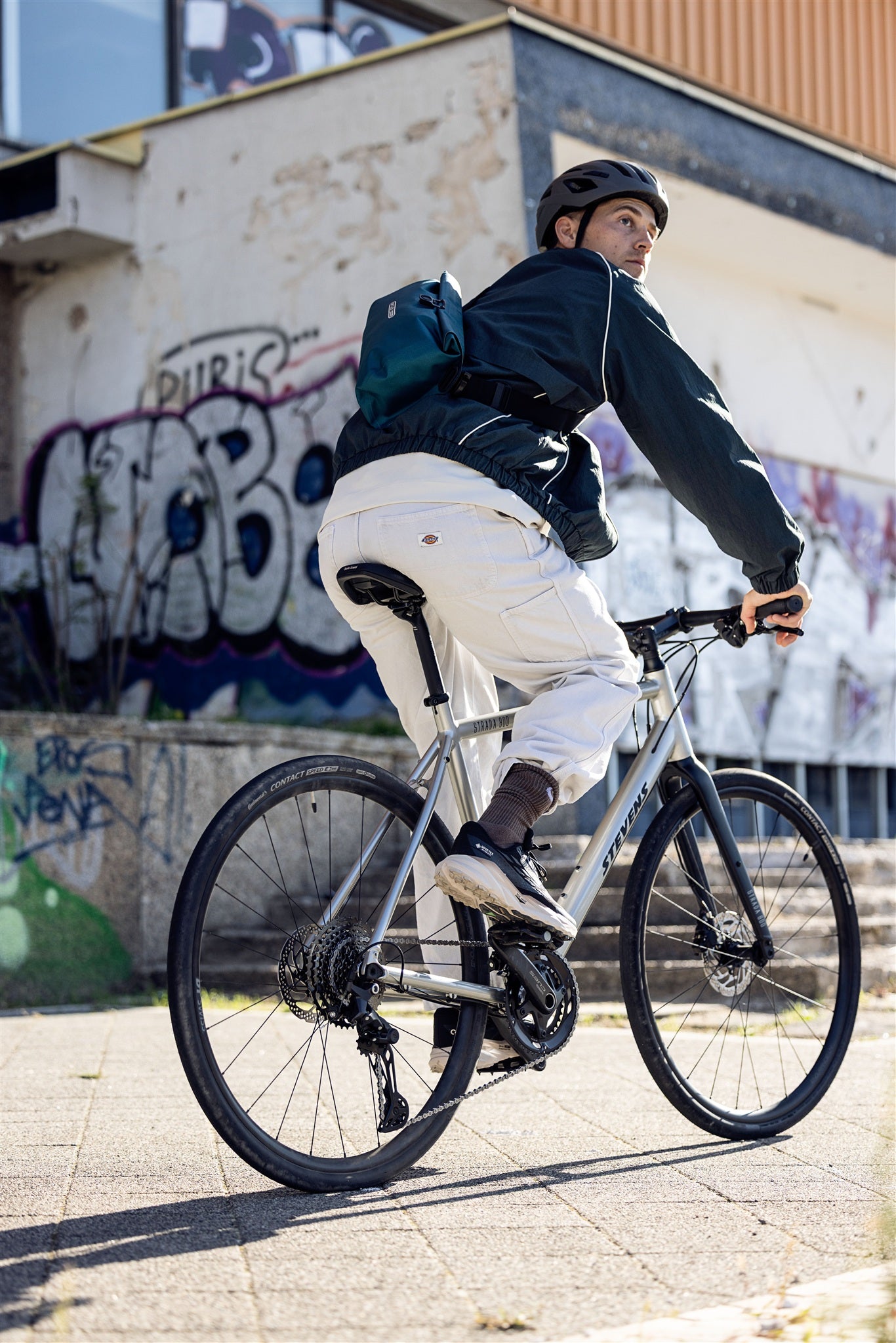 Ciclista con riñonera ORTLIEB Velo-Sling Flex color petróleo en entorno urbano con grafitis.