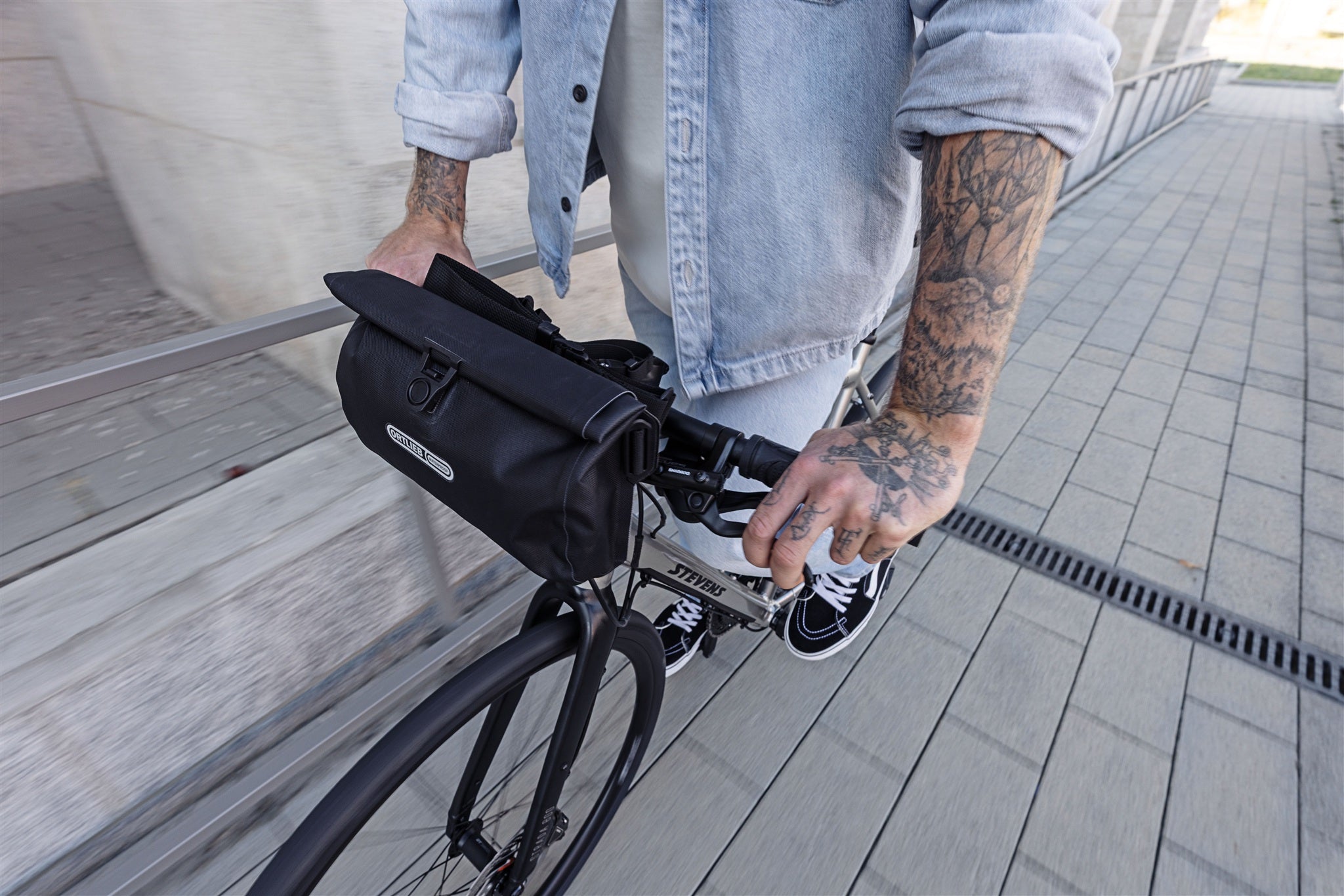Bolsa de manillar negra ORTLIEB Velo-Sling Flex con cierre enrollable y sistema Bar-Lock en bicicleta urbana.
