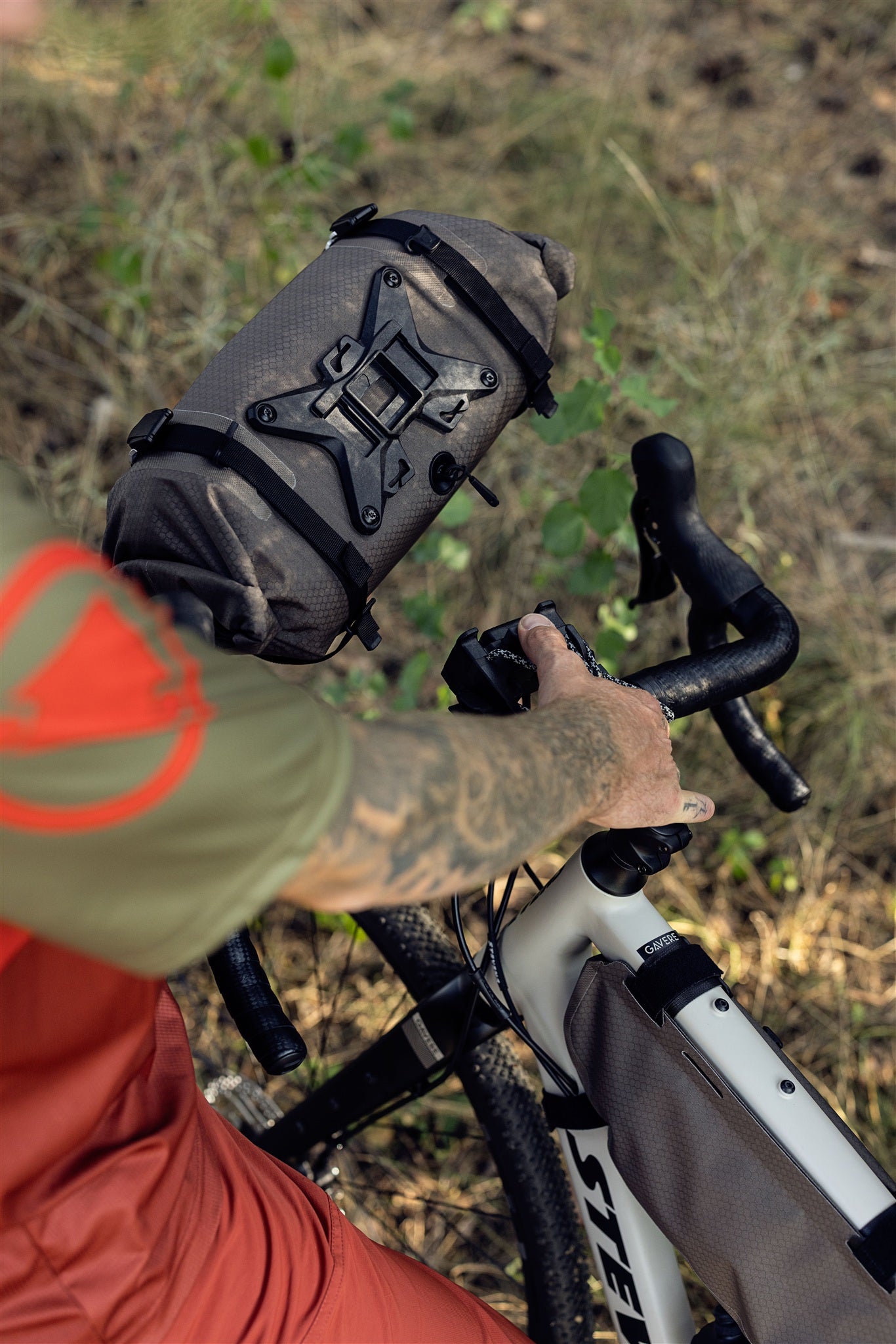 Ciclista con bolsa de manillar ORTLIEB Handlebar-Pack Flex color dark-sand en sendero forestal